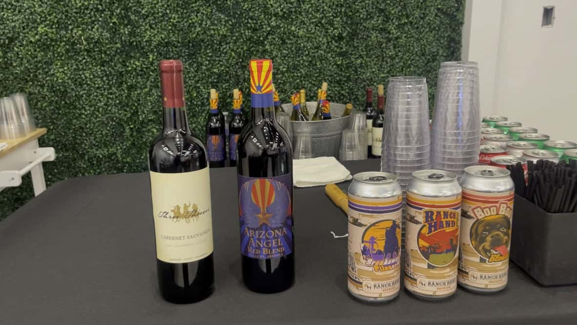 Event bar setup with a Cabernet Sauvignon, an Arizona red blend, three local craft beers, chilled white wine, sodas, and clear cups on a black linen table